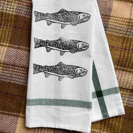 White towel with fish illustrations on a plaid fabric background