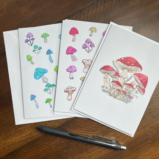 Set of greeting cards with mushroom designs on a wooden surface with a pen.