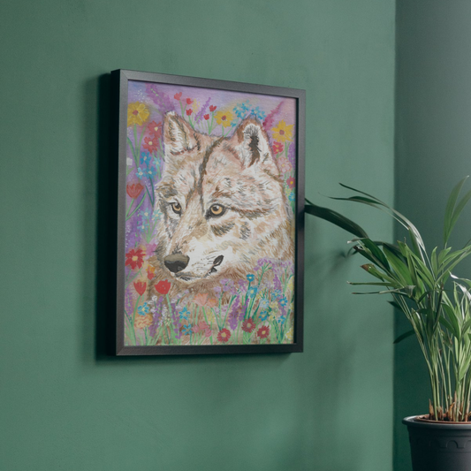 A framed pastel art print of a wolf surrounded by colorful wildflowers, hanging on a dark green wall next to a potted plant.