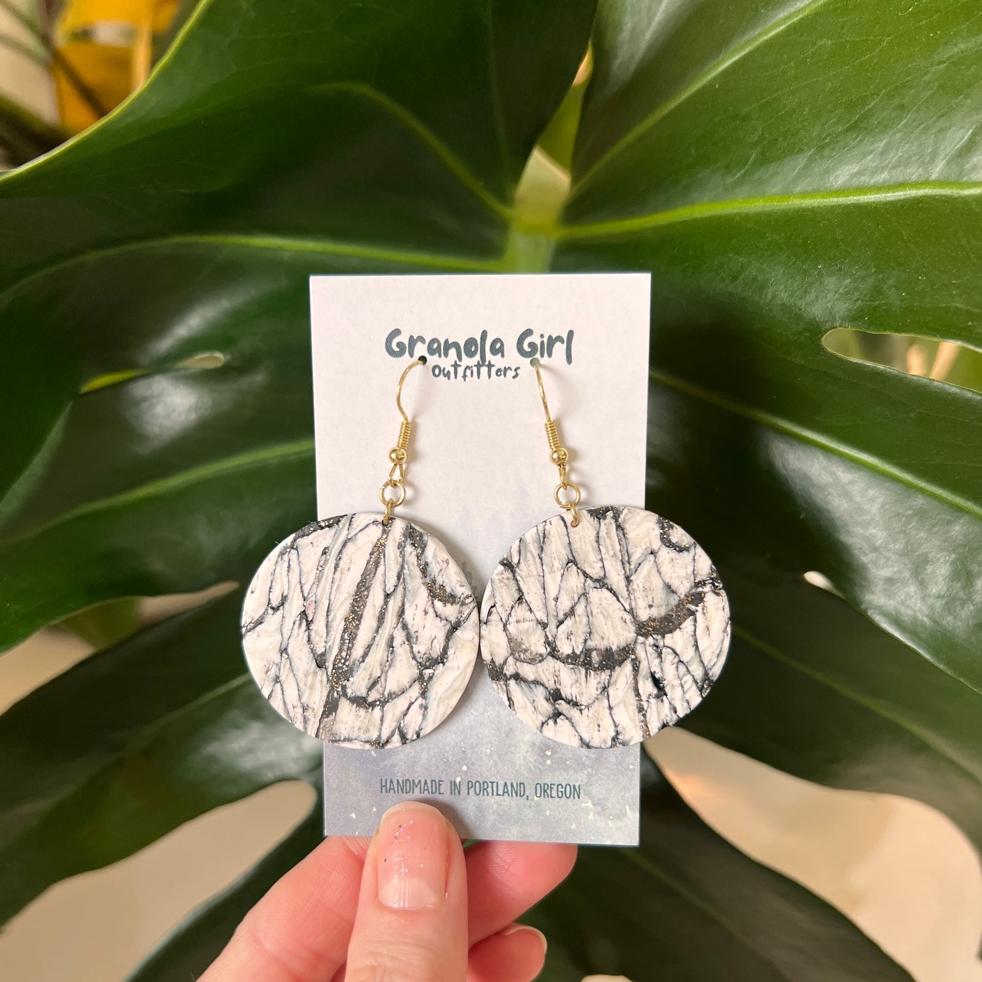Marble-patterned earrings on a 'Granola Girl' branded card with green leaves in the background
