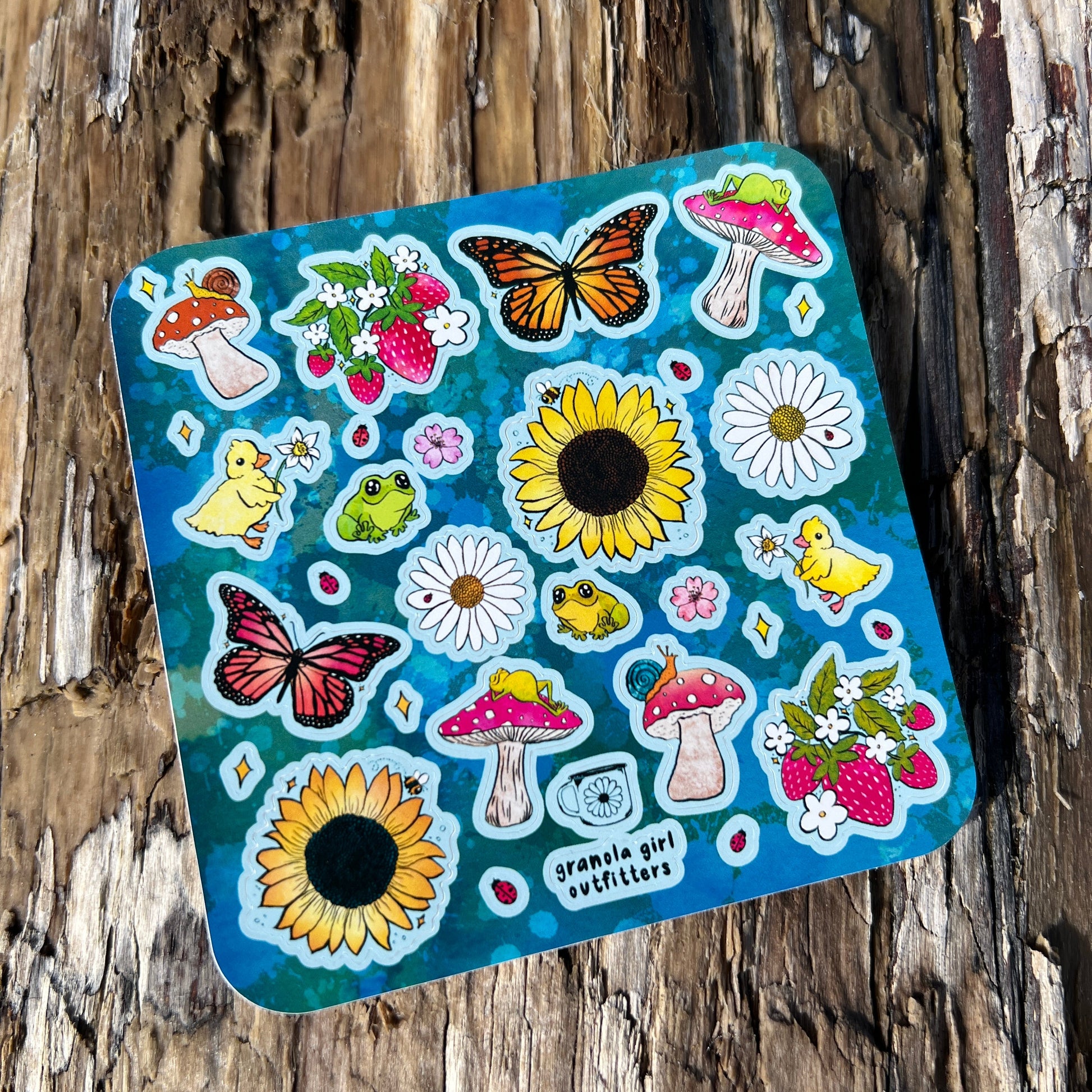 A sheet of colorful spring-themed stickers featuring designs such as butterflies, mushrooms, and sunflowers, placed on a wooden surface.