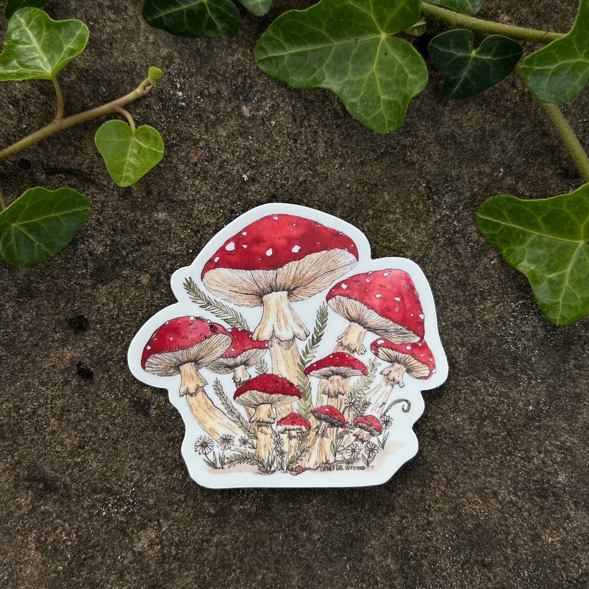 Sticker of red mushrooms with white spots on a textured surface with green leaves.