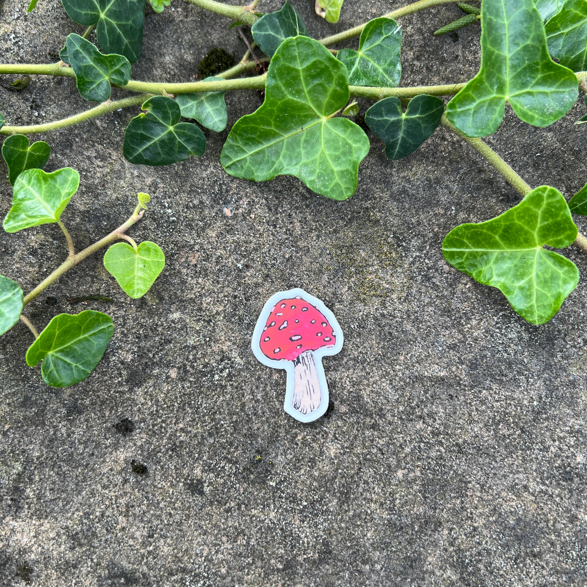 Sticker of a mushroom on rocky surface with green leaves