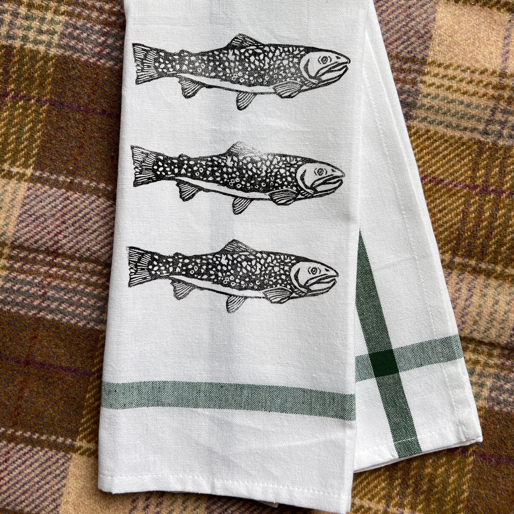 White towel with fish illustrations on a plaid fabric background