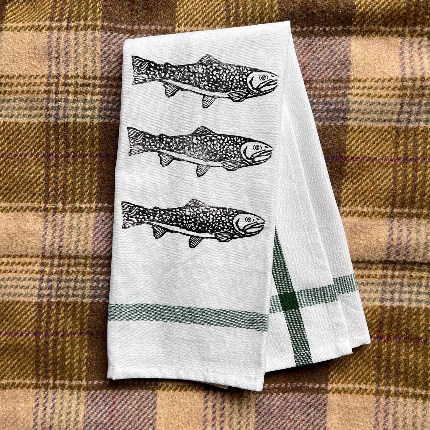 Two white towels with fish design on a plaid fabric background