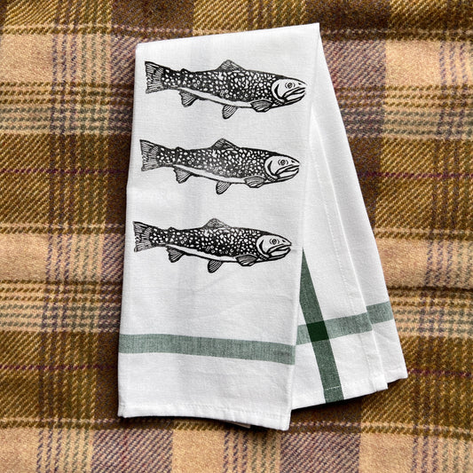 Two white towels with fish design on a plaid fabric background