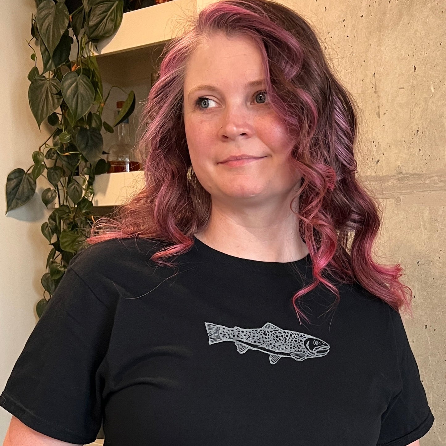 Person wearing a black t-shirt with a fish design, standing indoors.