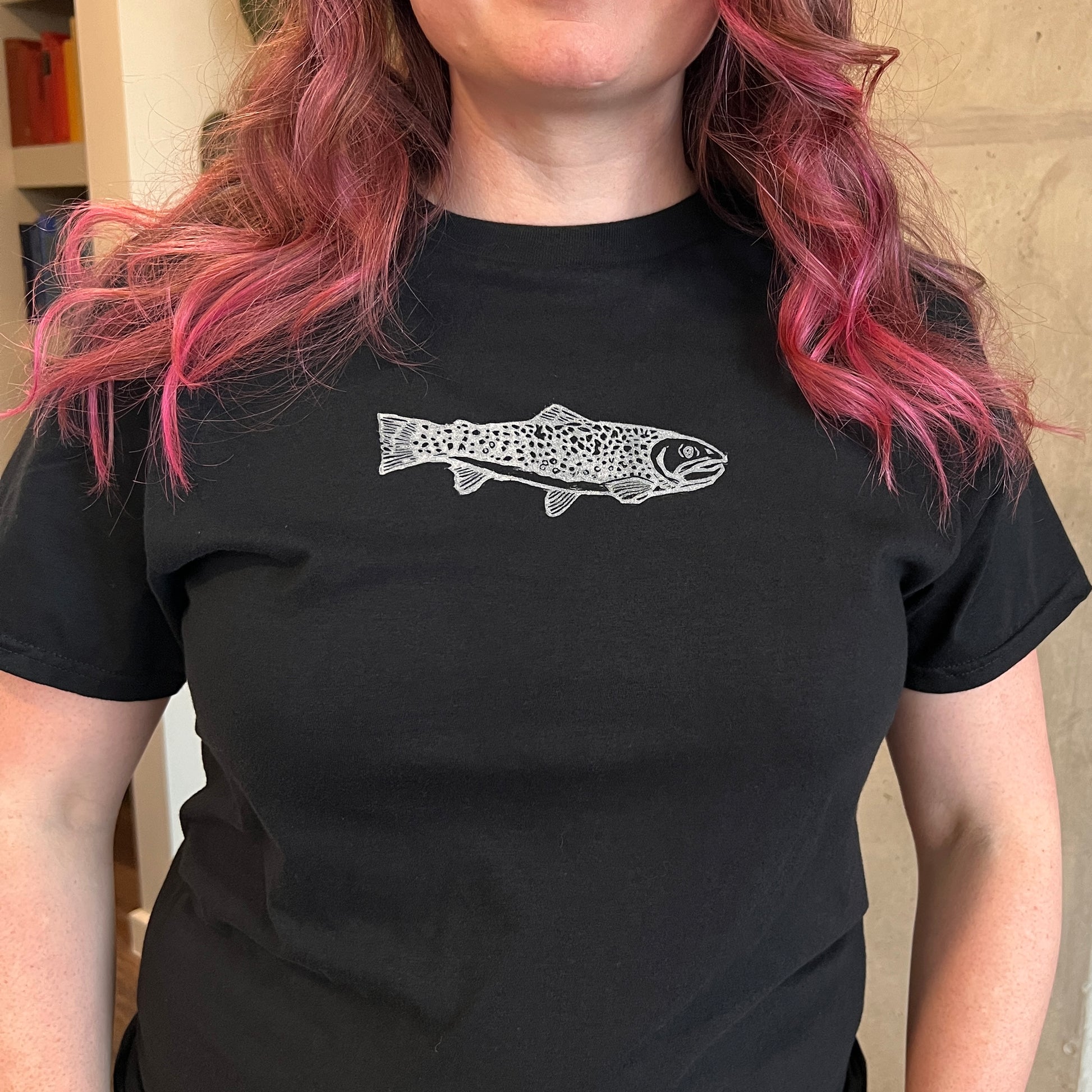 Person wearing a black t-shirt with a white fish design.