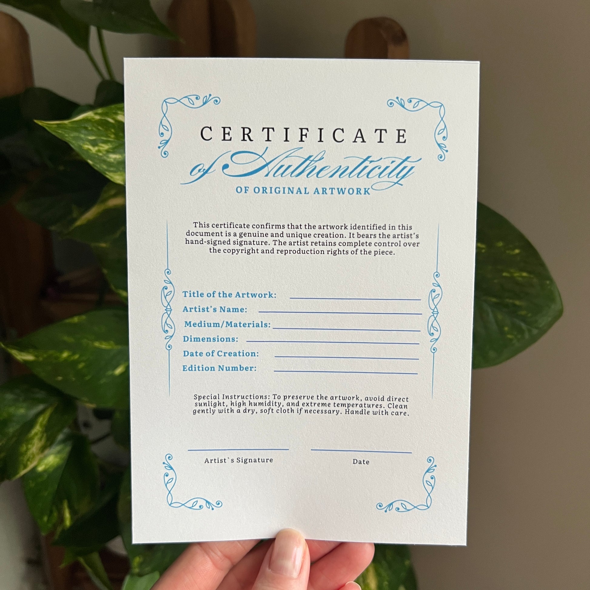Certificate of Authenticity for original artwork held in front of a plant