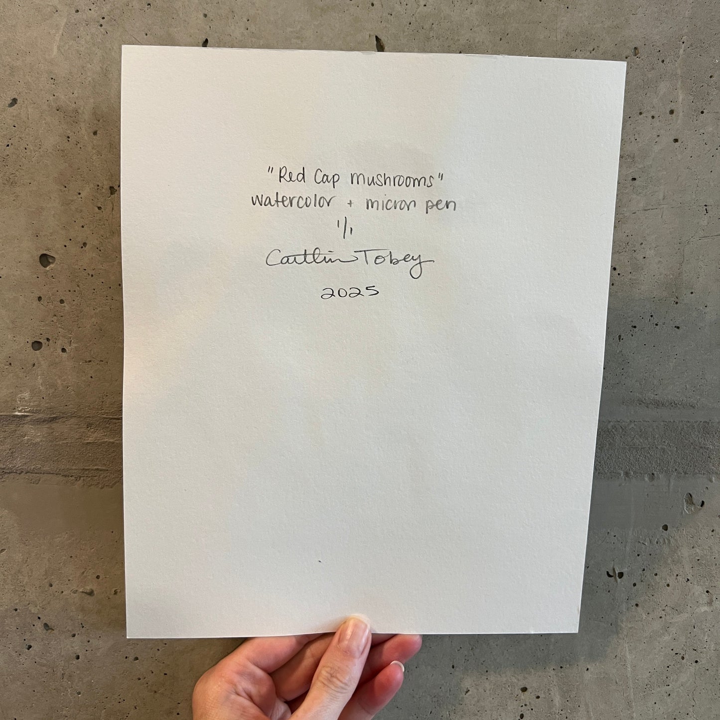 Hand holding a white card with text on a concrete surface