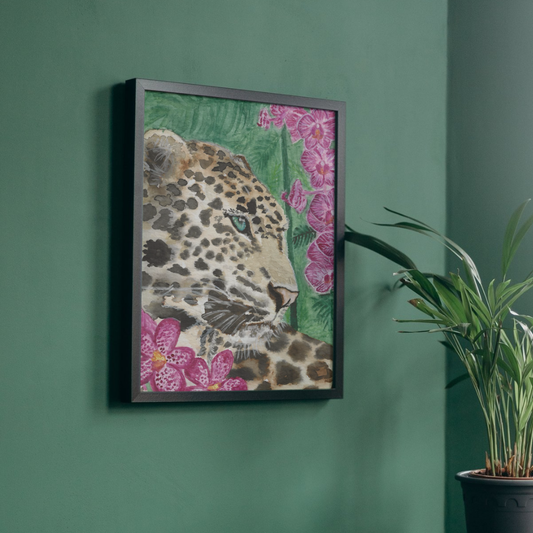 Framed wall art featuring a close-up leopard illustration with pink flowers and green foliage, hung on a dark green wall next to a potted plant.
