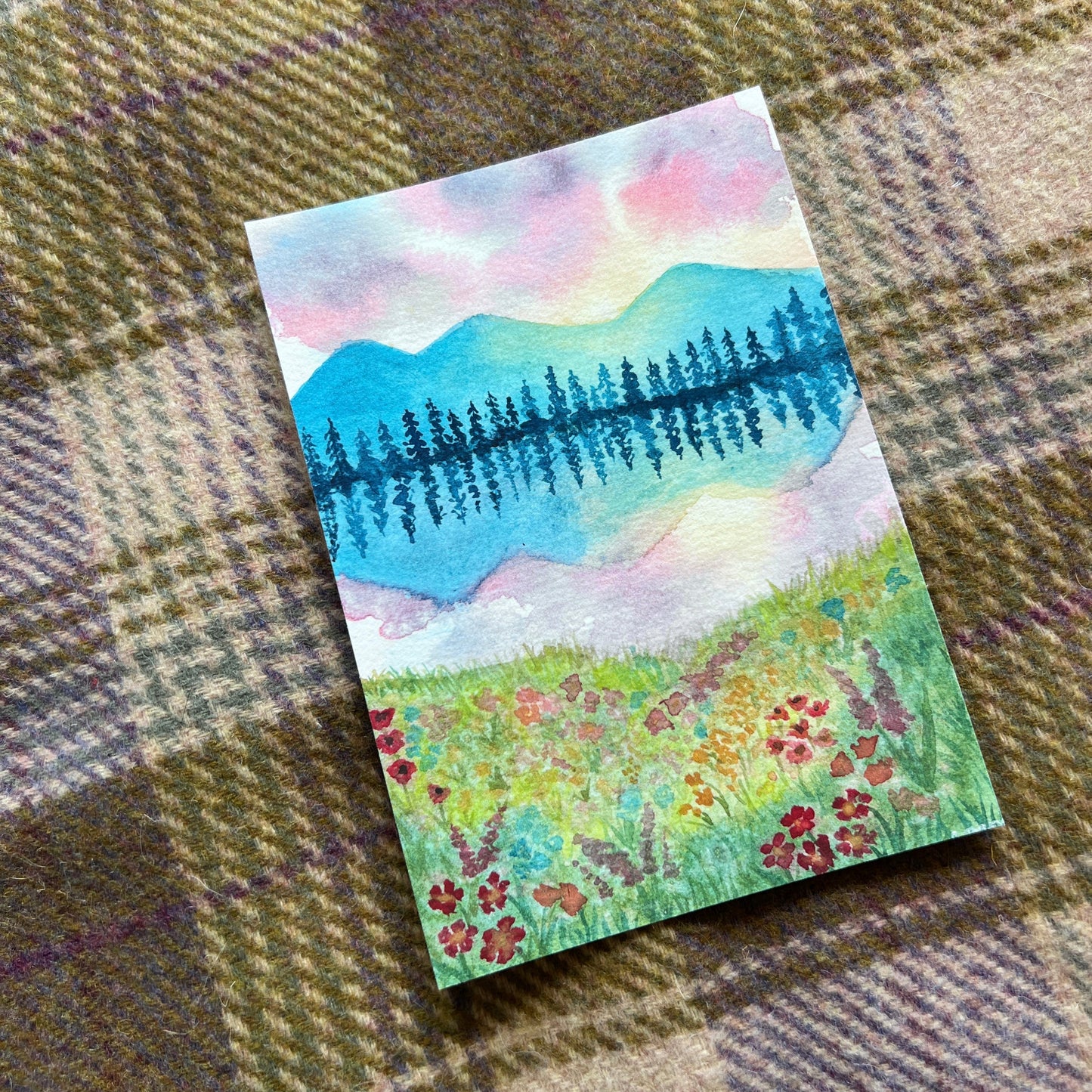 Colorful watercolor painting of a landscape on a textured fabric background