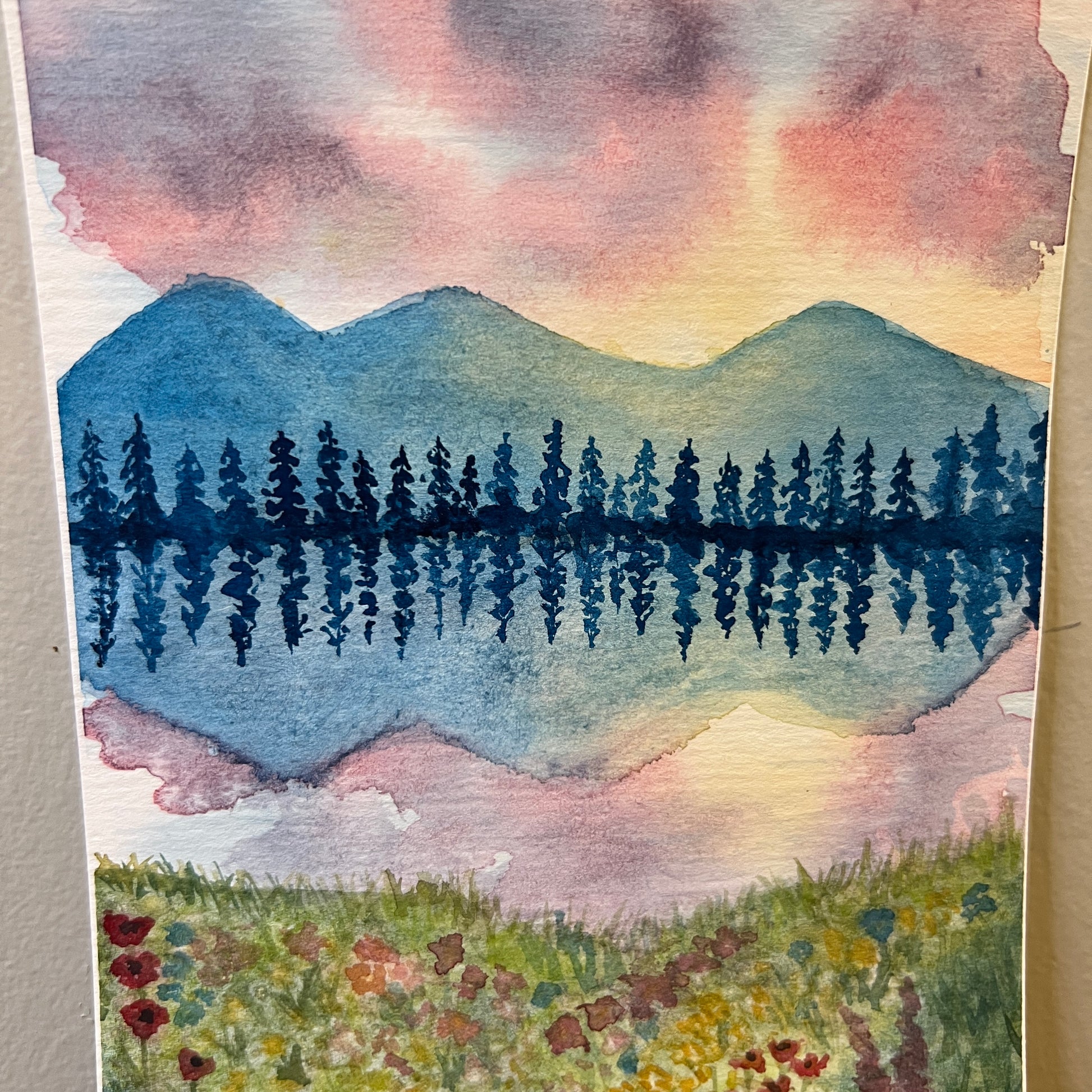 Watercolor painting of a landscape with mountains, trees, and flowers.