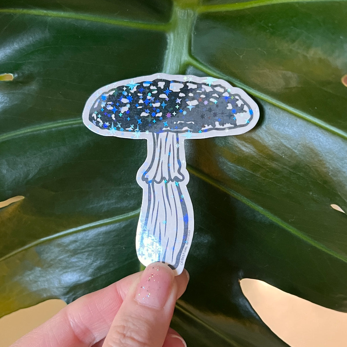 Holographic mushroom sticker being held up by a hand