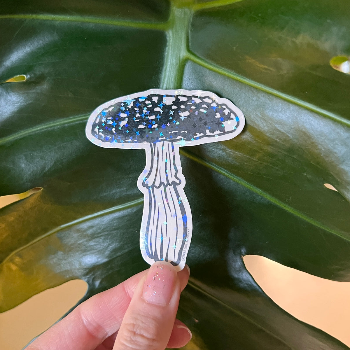 Sticker of a mushroom held over a large green leaf