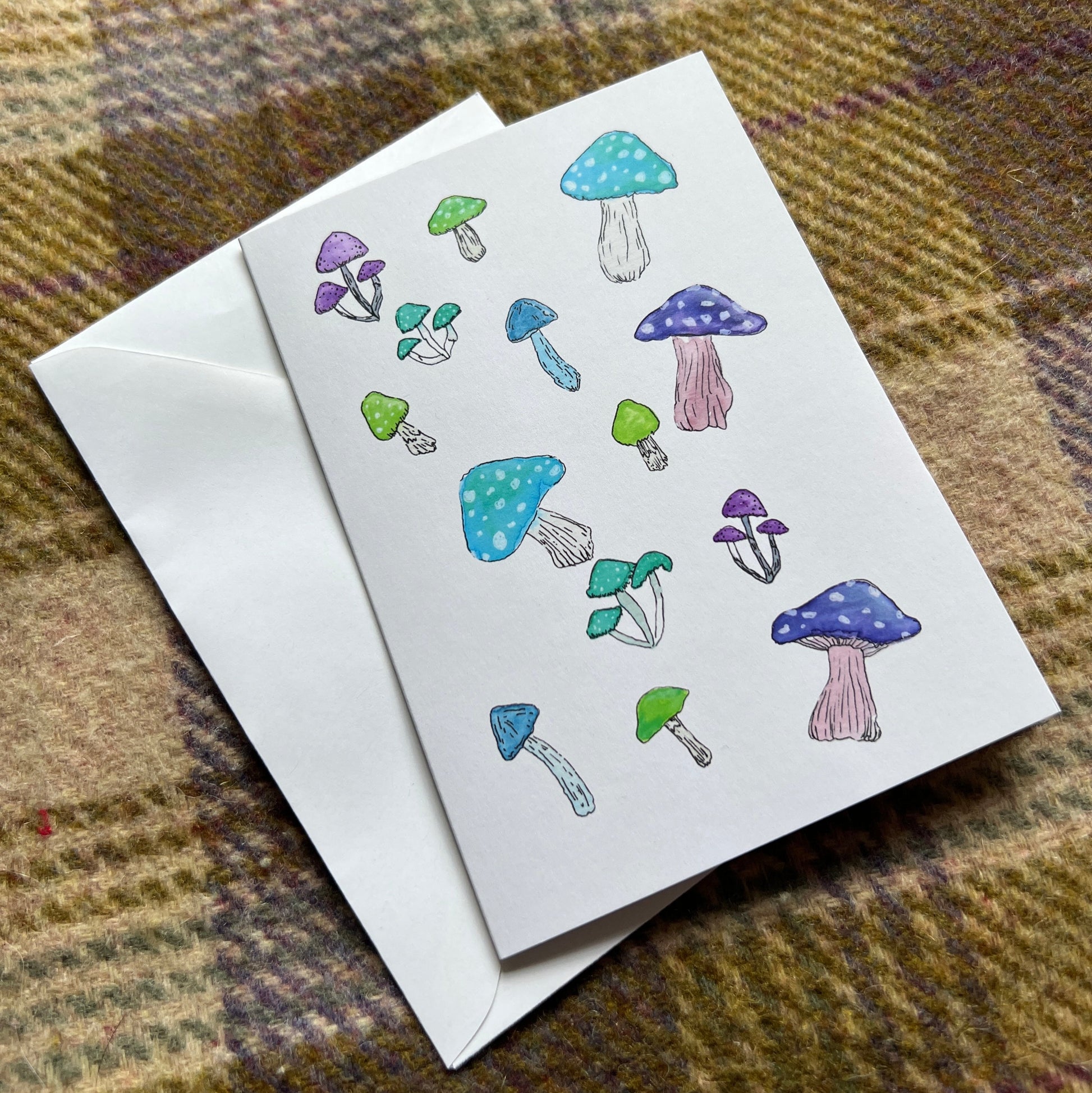 Card with mushroom illustrations on a plaid fabric background